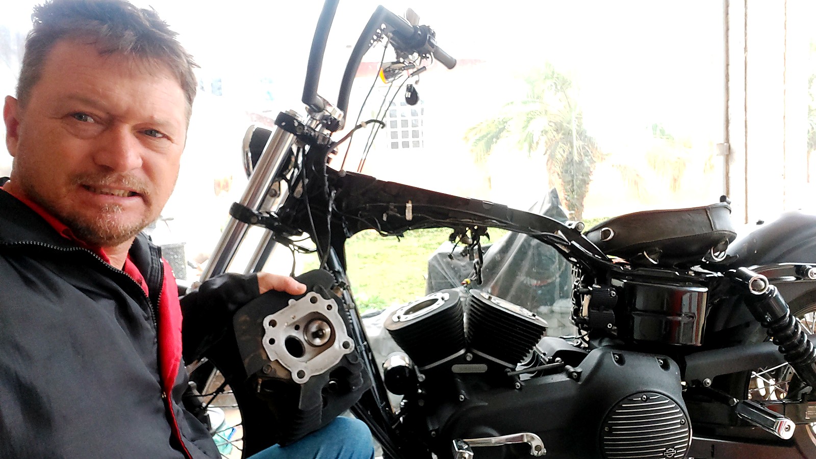 Jairo na oficina com uma Harley-Davidson desmontada para manutenção